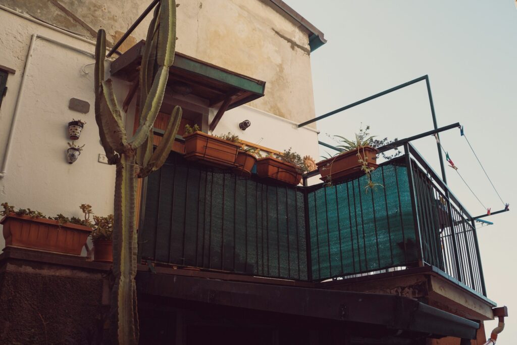 Balkon mit grüner Bespannung am Geländer und Topfpflanzen als Balkon Sichtschutz