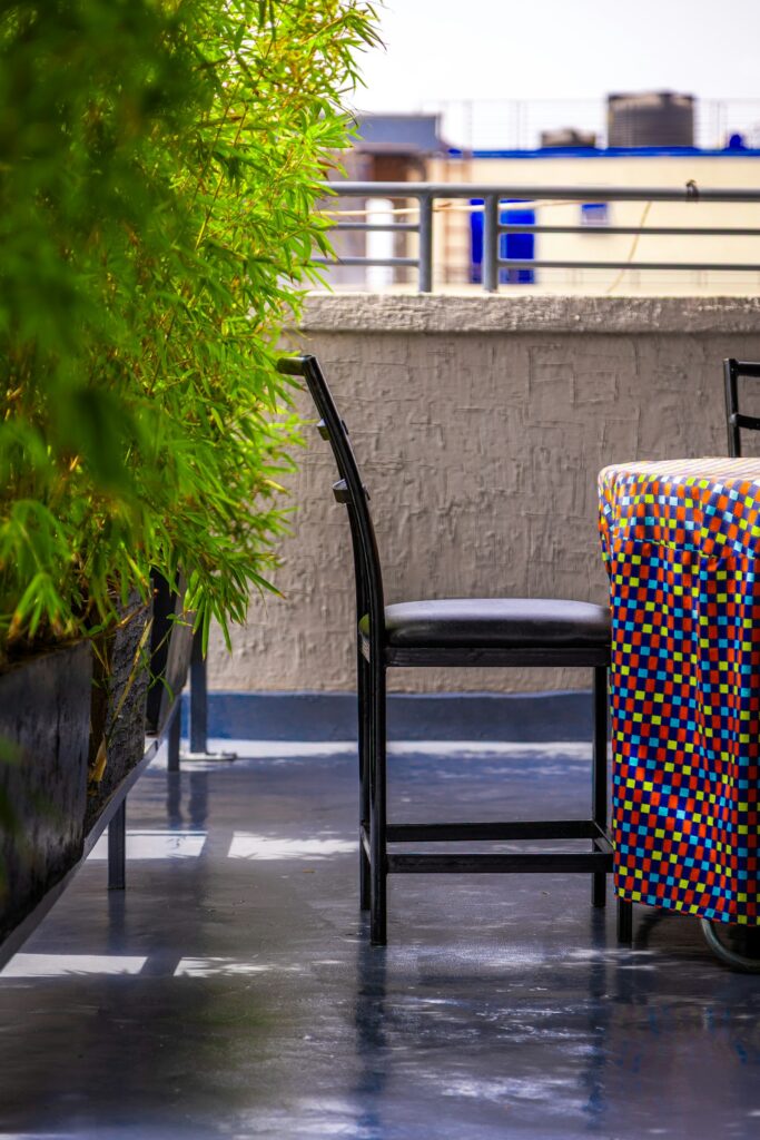 Dachterrasse mit Stuhl, buntem Tisch und grünem Bambus im Kübel als Sichtschutz