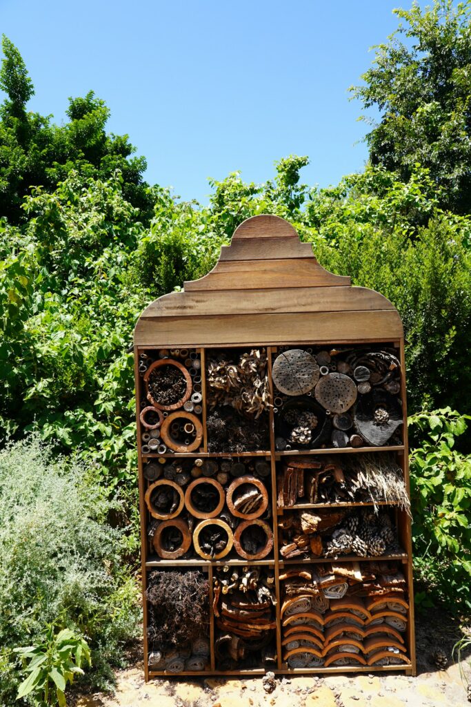 Großes Insektenhotel aus Holz in einem bepflanzten Garten mit viel Nahrungsangebot